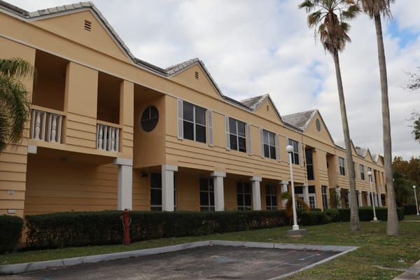 Exterior view of a nursing home building with palm trees