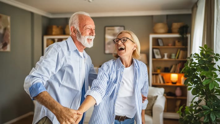 Two smiling residents dancing together in a cozy living area