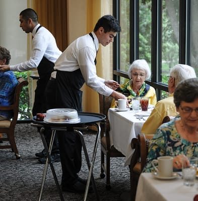 Staff serving food to residents in a dining room