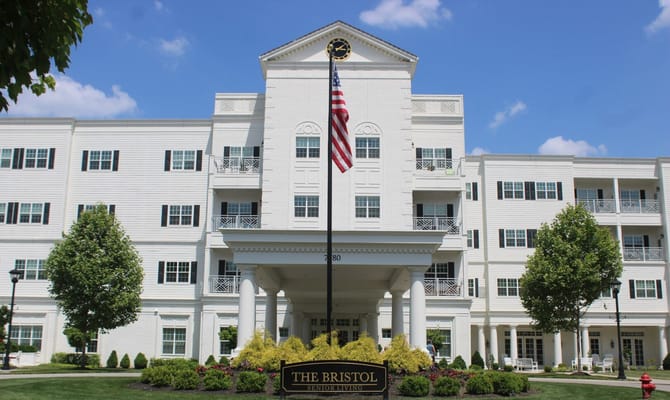 Exterior view of The Bristol Senior Living facility with an American flag.