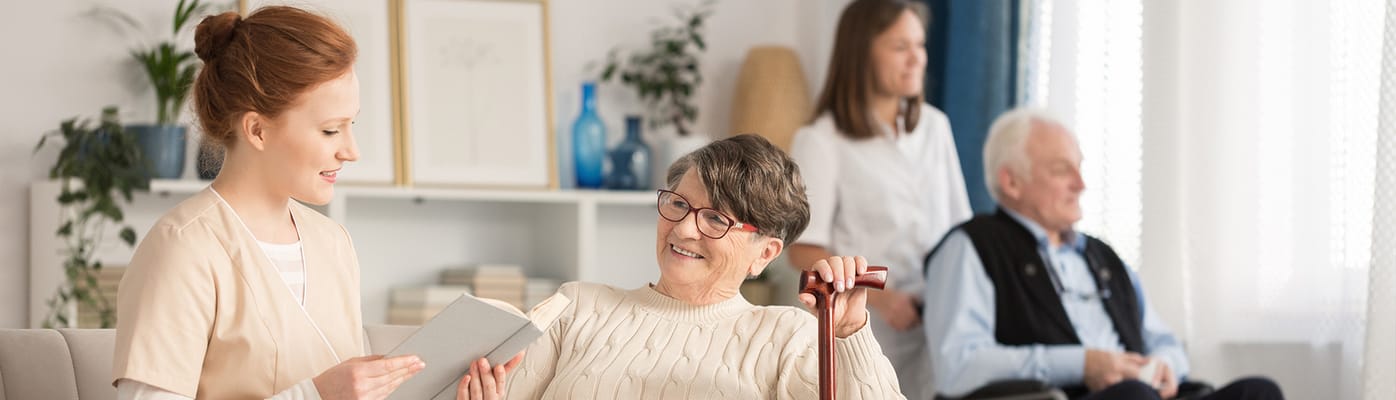 A caregiver reading to a resident in a cozy living room