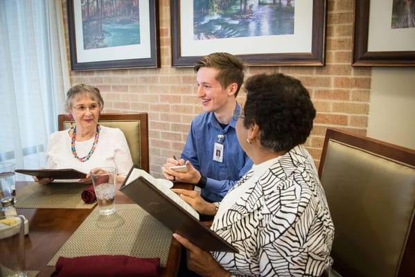 Residents and staff at a dining area looking at menus