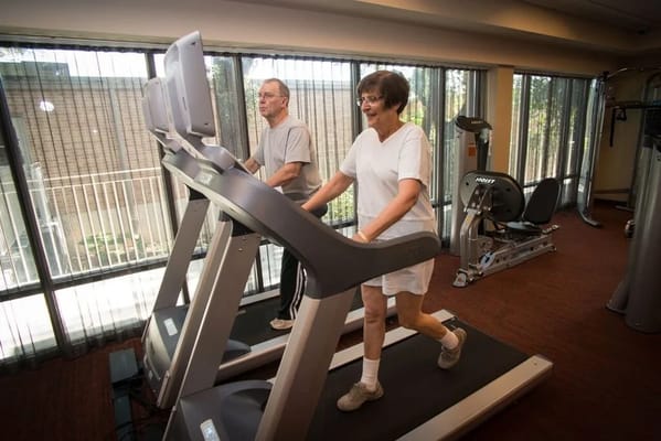 Residents exercising on treadmills in a fitness room