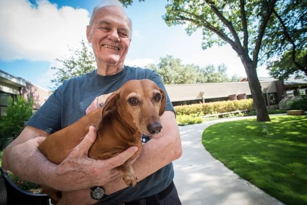 A resident joyfully holding a dog in the garden
