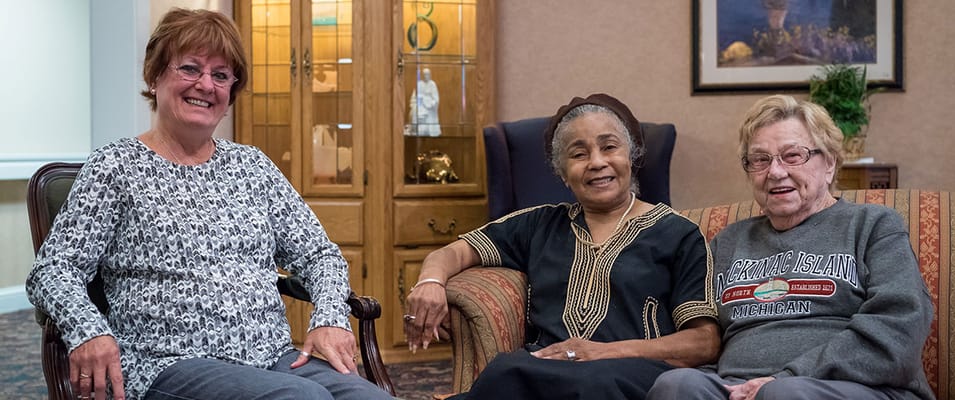 Three residents interacting in a cozy lounge area