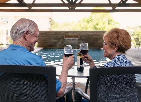 Two residents toasting with glasses of wine by the pool