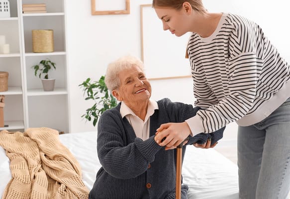 Caregiver assisting a smiling senior in a cozy room