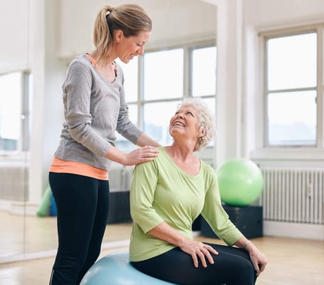 A staff member assisting a senior resident during an exercise session