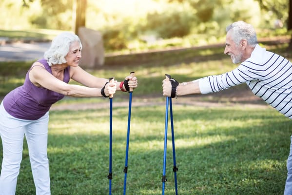 Elderly couple engaging in outdoor exercise using walking poles
