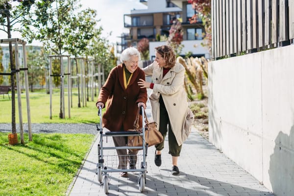 Resident smiling with staff member in outdoor garden