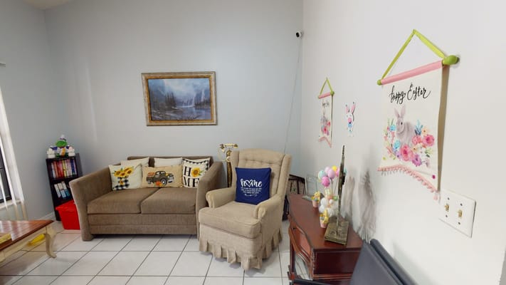 Living room with a sofa, armchair, and decorative wall hangings.