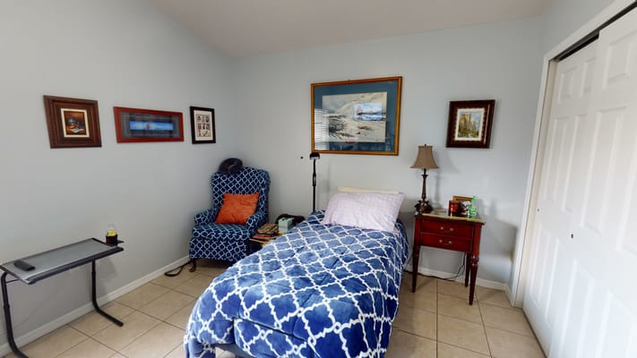Cozy bedroom setup with a bed, blue patterned blanket, and a chair
