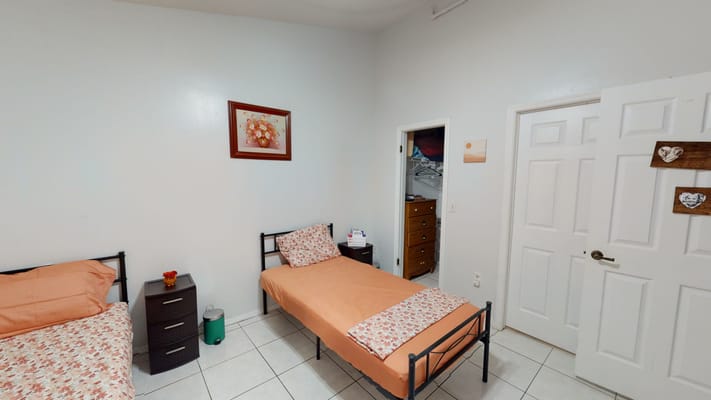 A cozy bedroom with two beds, each with floral bedding, and a dresser in the corner.
