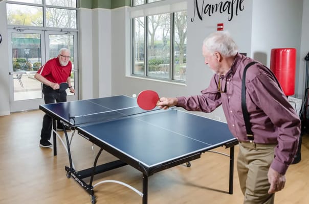 Two residents playing table tennis in an activity room