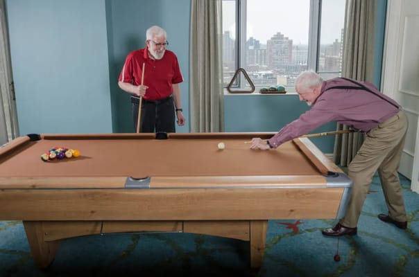 Two senior men playing pool in a recreational room