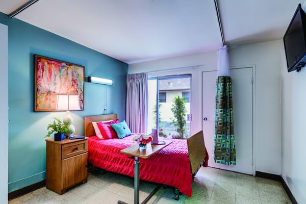 A brightly colored private resident room with a bed and decor