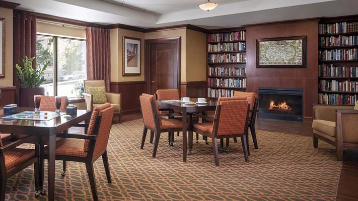 Library with bookshelves, a fireplace, and seating area.