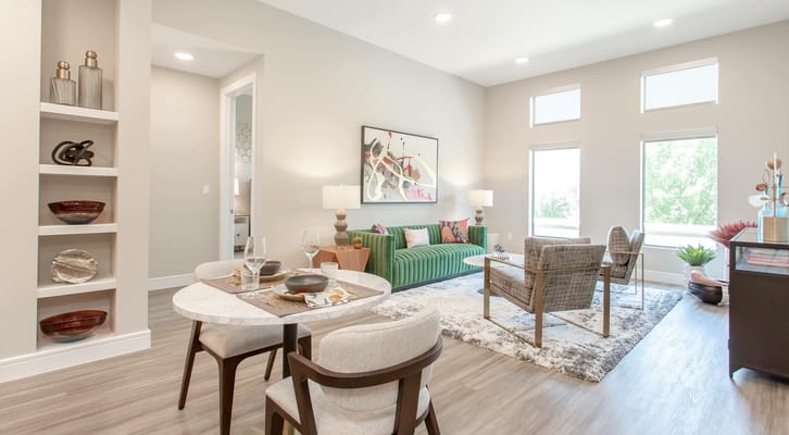 A modern living room with green sofa, dining table, and decorative elements.