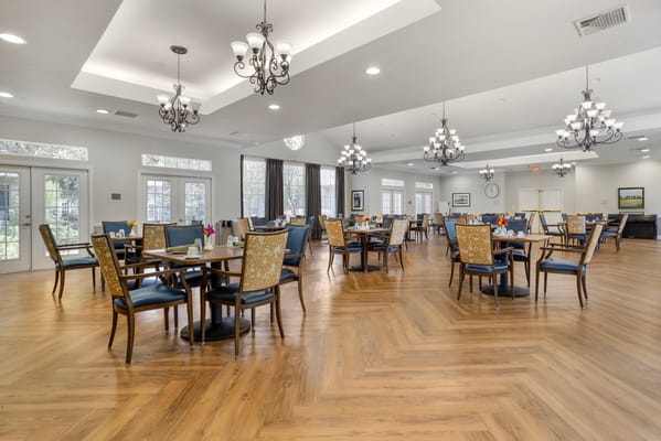 Bright dining room with tables and chairs in Braeswood Estates Senior Living.