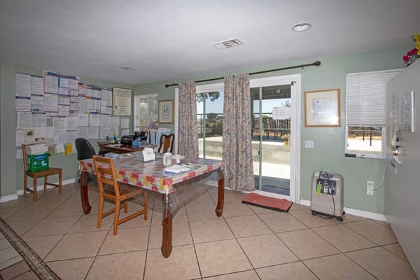 Interior view of the common area with a table and chairs, and a sliding glass door.