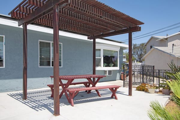 Wooden picnic table under a pergola in an outdoor seating area
