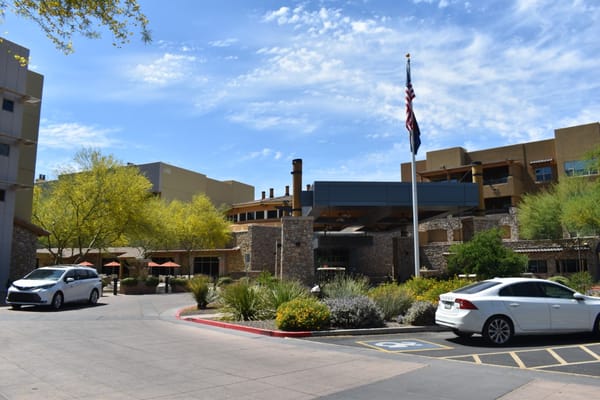 Main entrance of Sagewood senior living facility with flag and landscaping.