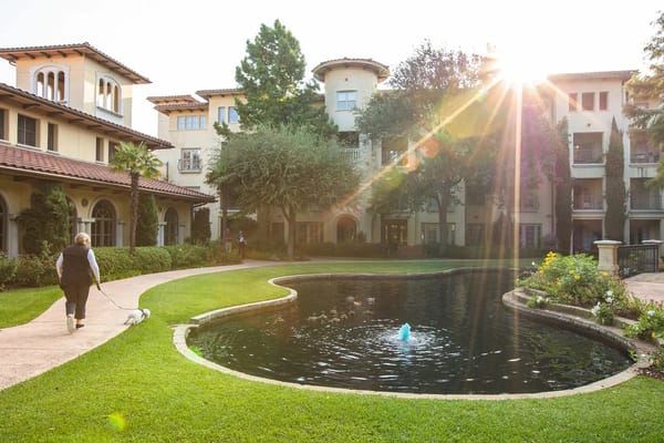 A woman walks her small dog along a pathway in the garden at Edgemere.