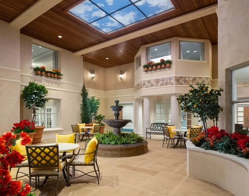 An inviting indoor courtyard with a fountain, seating, and vibrant plants.
