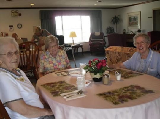 Three residents at a dining table enjoying a meal