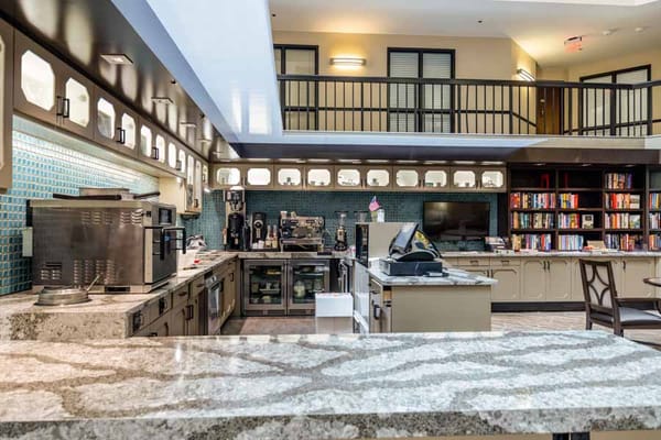 A modern kitchen with granite countertops and coffee station in a senior living facility.