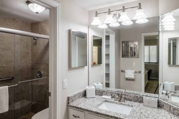 Modern bathroom with granite countertop and shower.