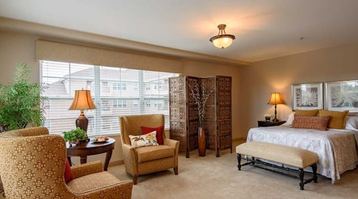 A well-furnished bedroom with a bed, decorative screen, and comfortable seating.