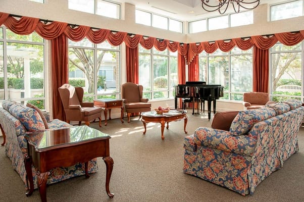 Spacious living room with floral sofas and a grand piano.