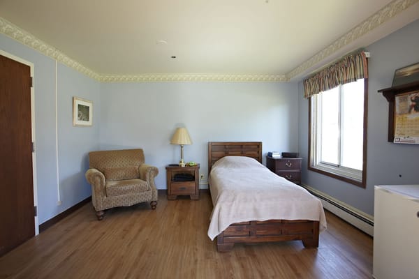 A private resident room with a bed and chair