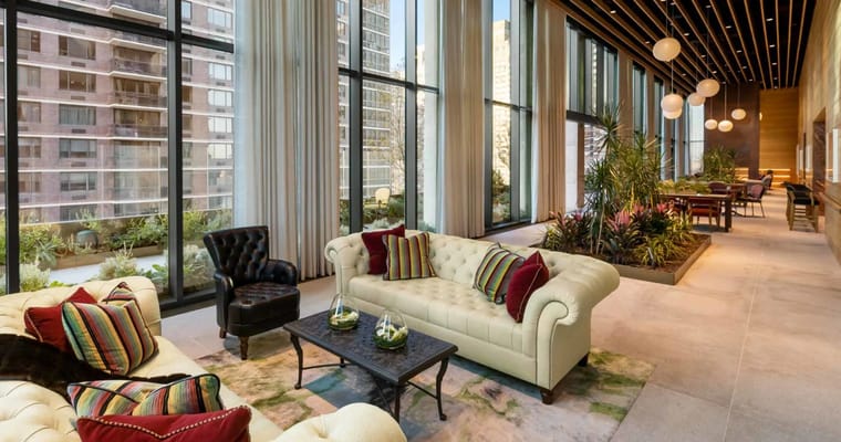 Cozy lounge with large windows and plush seating at Inspīr Carnegie Hill