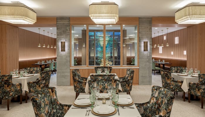 Dining room with floral chairs and tables set for a meal