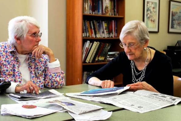 Two residents reading newspapers in a common area