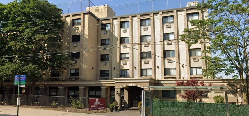 Front view of Kings Adult Care Center building with trees and a bus stop.