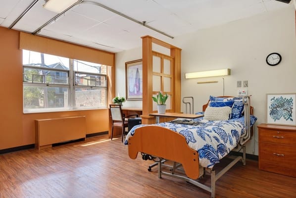 A cozy resident room with a hospital bed and artwork