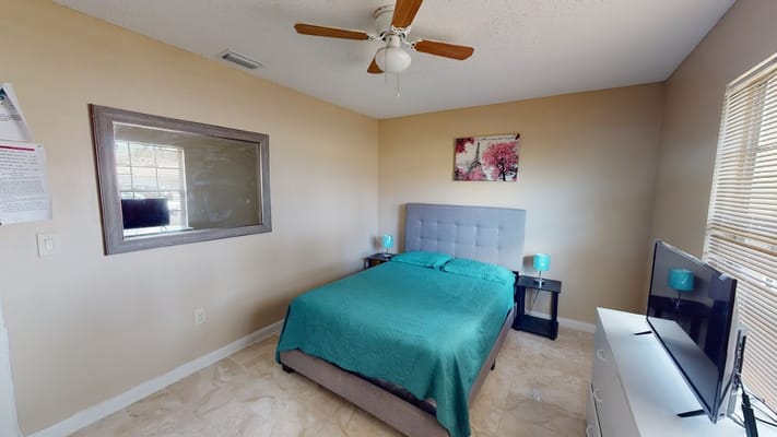 Bright bedroom with a queen-sized bed and TV