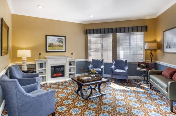 A cozy living room with blue chairs, a fireplace, and decorative flooring