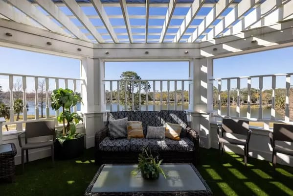 Serene patio with seating and lush plants overlooking a lake