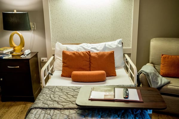 Bedroom featuring a bed with orange pillows and a small table