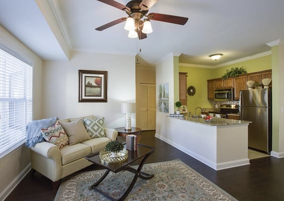 Living room area with a sofa and kitchen view in a senior living facility.
