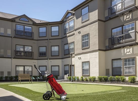 Putting green with golf clubs and balls in a courtyard setting