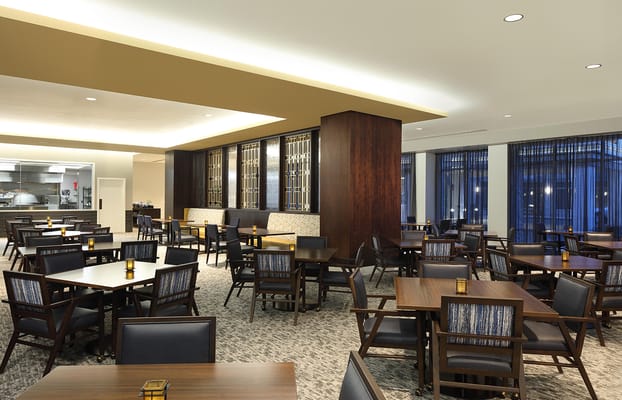 Spacious dining room with wooden tables and chairs, featuring ambient lighting.