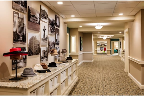 A hallway with hats displayed on a countertop and black-and-white photos on the walls.