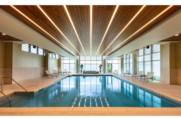 Indoor swimming pool area with lounge chairs and modern lighting.