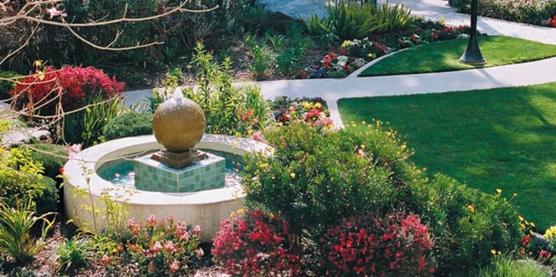 A landscaped garden featuring a fountain and colorful flowers.
