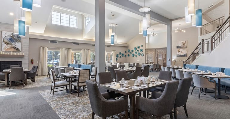 Bright dining room with tables set for meals and decorative lighting.